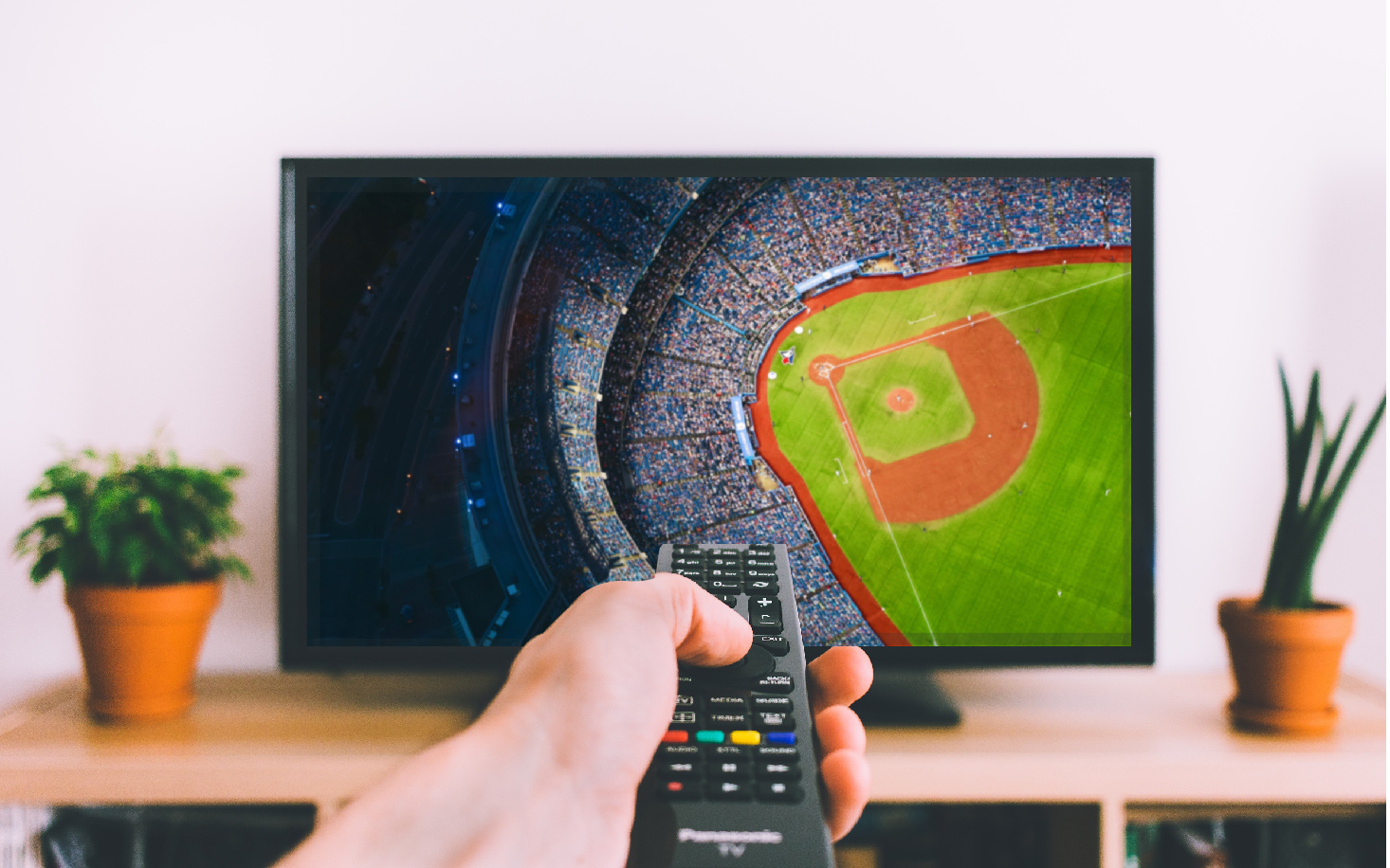 man holding a remote control while watching the baseball game