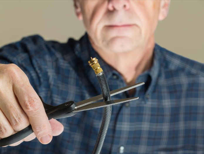 man cutting a cable cord with a pair of scissors